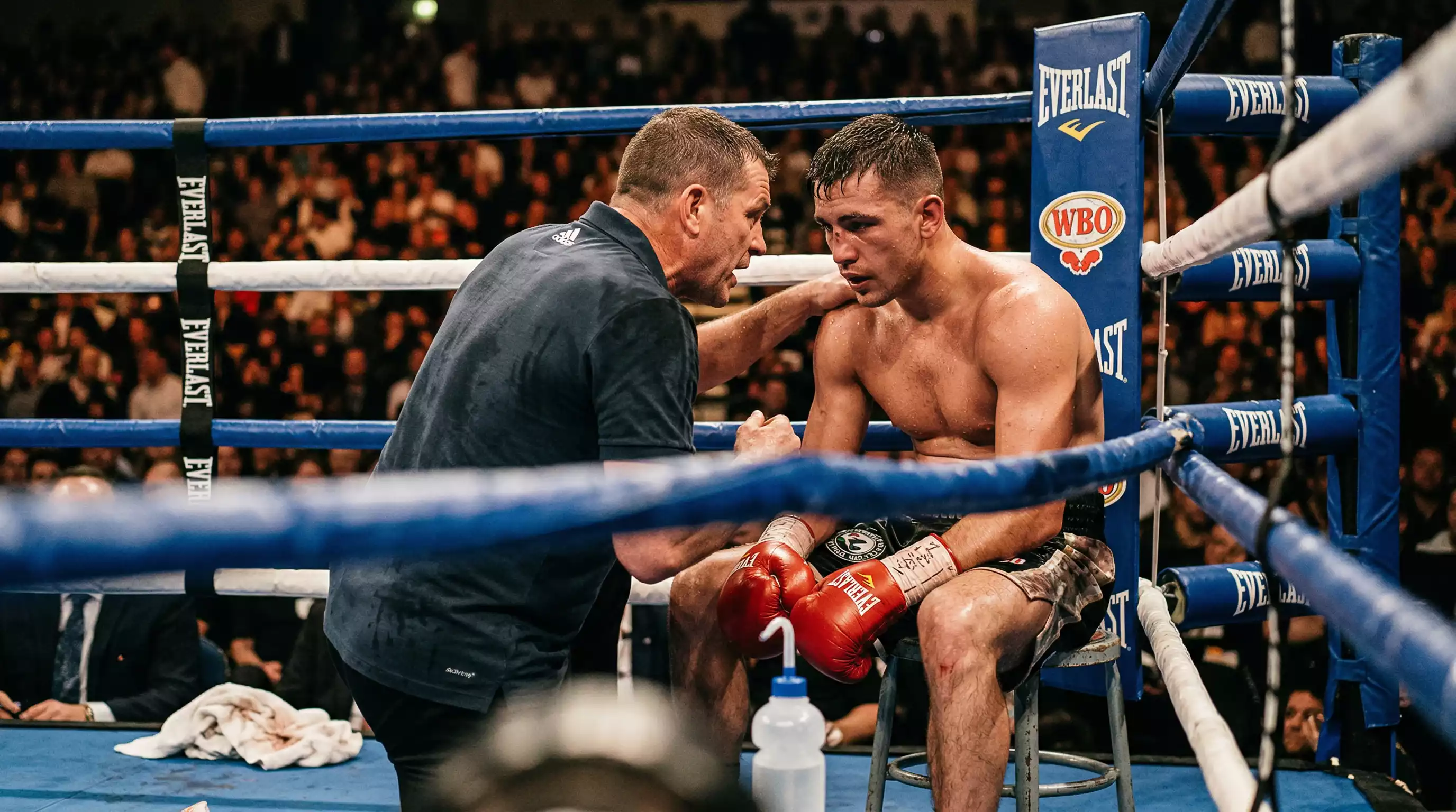 Boxkampf Analyse – Trainer bespricht Strategie mit einem Boxer in der Ecke